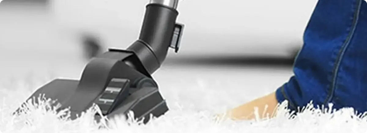 Close-up of a professional vacuuming a white carpet in Fontana.